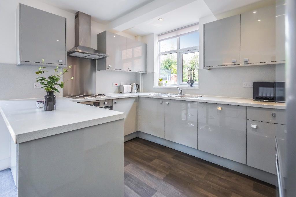 Modern gloss kitchen with bright window and isl...