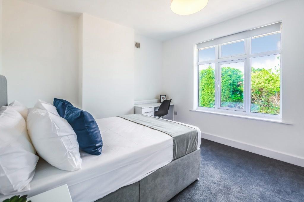 Bright, tidy bedroom with desk and large window...