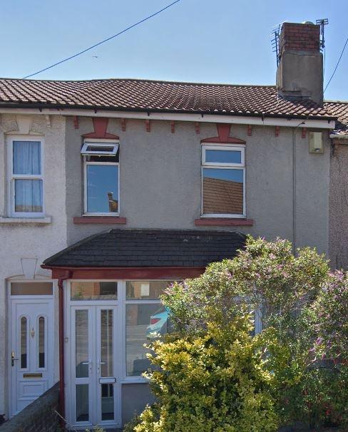 Terraced house front with porch and mature shru...