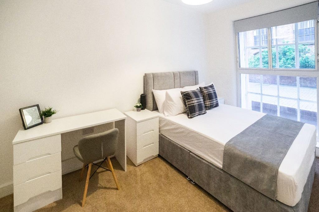 Bright, neatly furnished bedroom with desk and ...