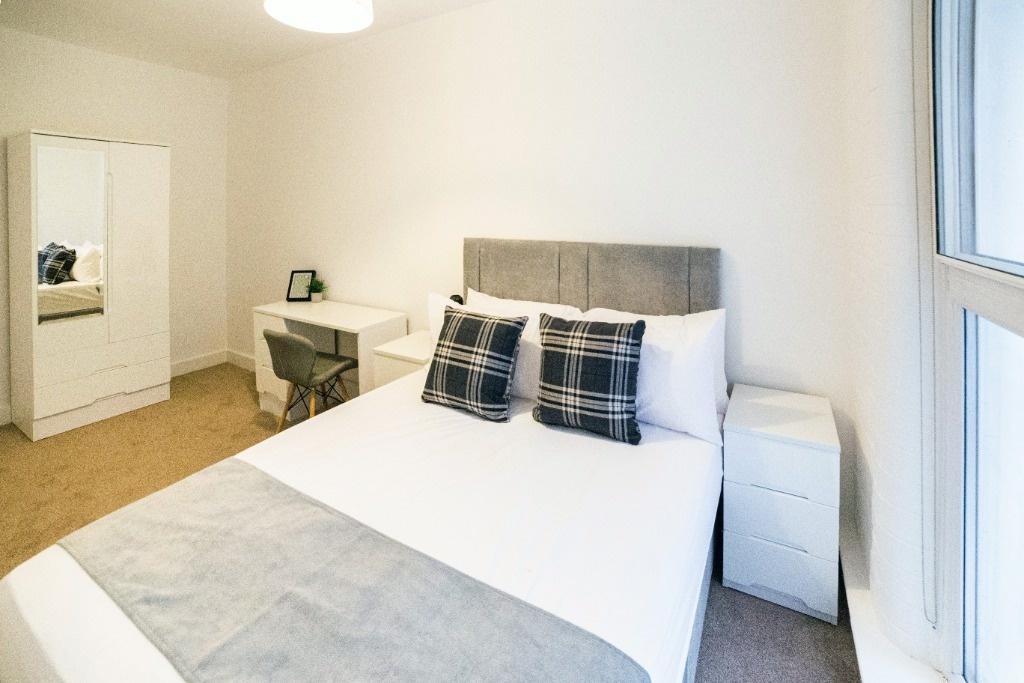 Bright, tidy bedroom with desk and built-in mir...