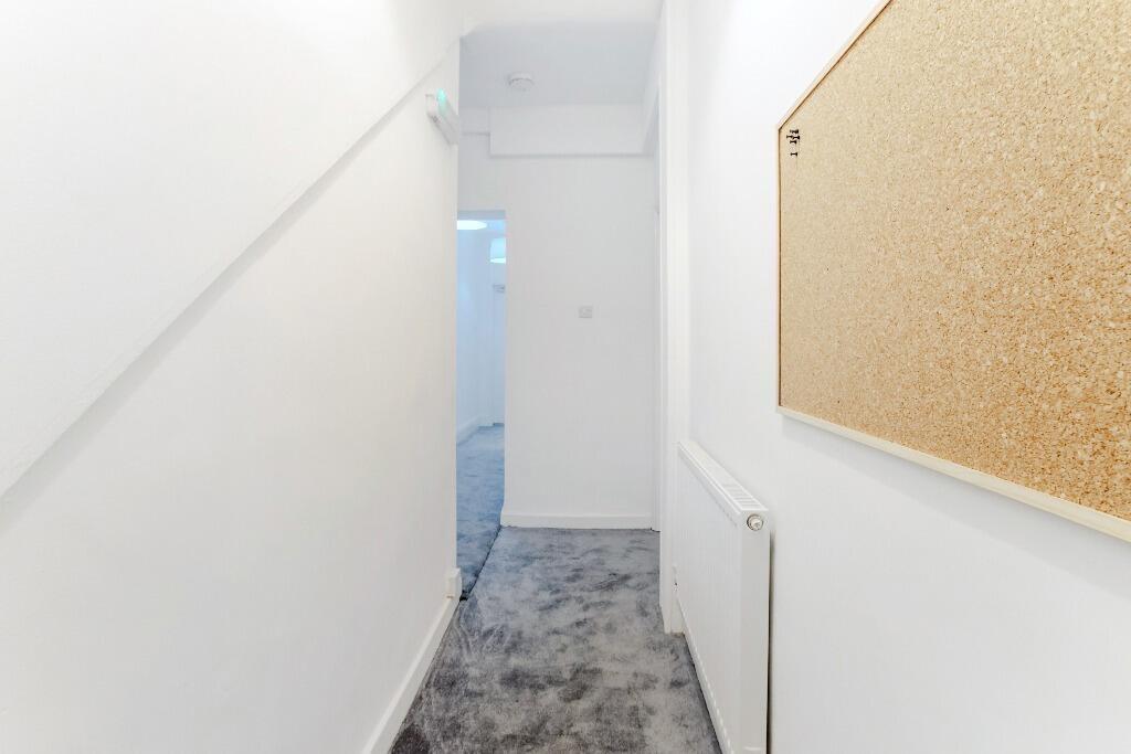 Bright narrow hallway with noticeboard and carp...