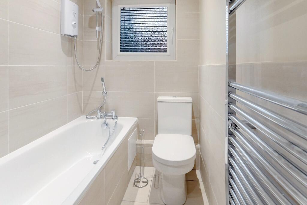 Bright modern bathroom with bath and heated rai...