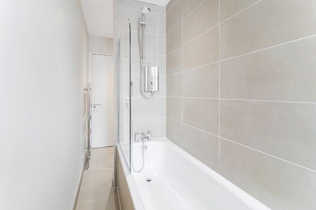 Modern bathroom with tiled bath and shower...