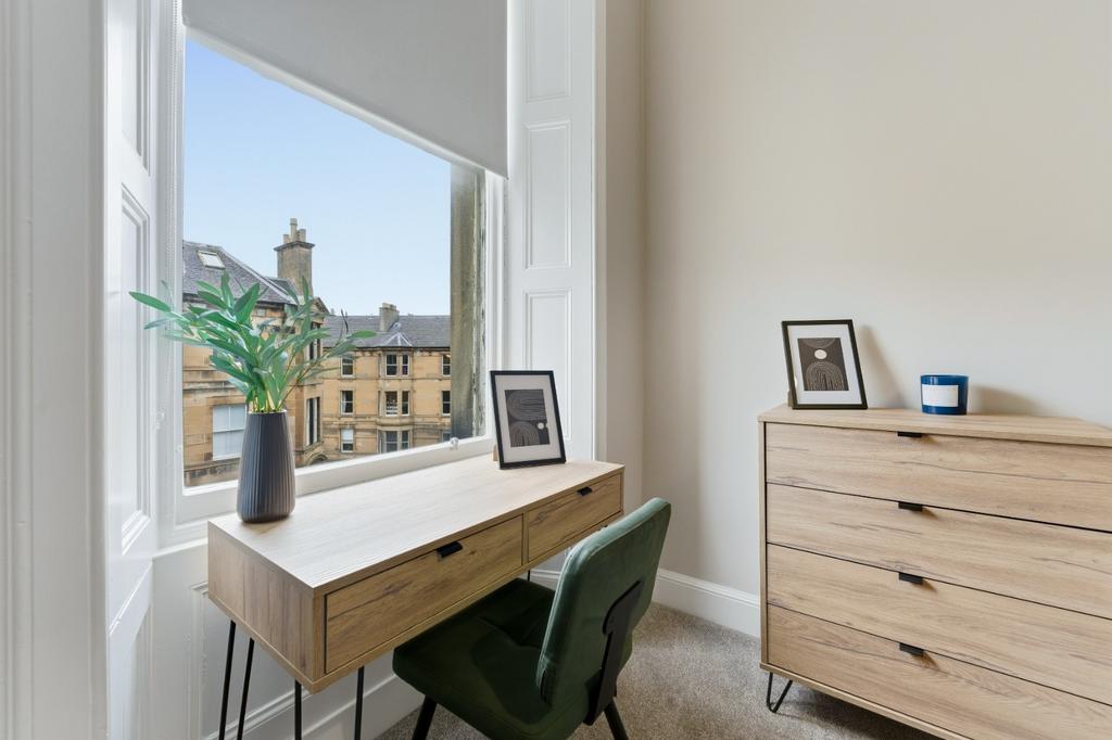 Bright bedroom with desk and large sash window...
