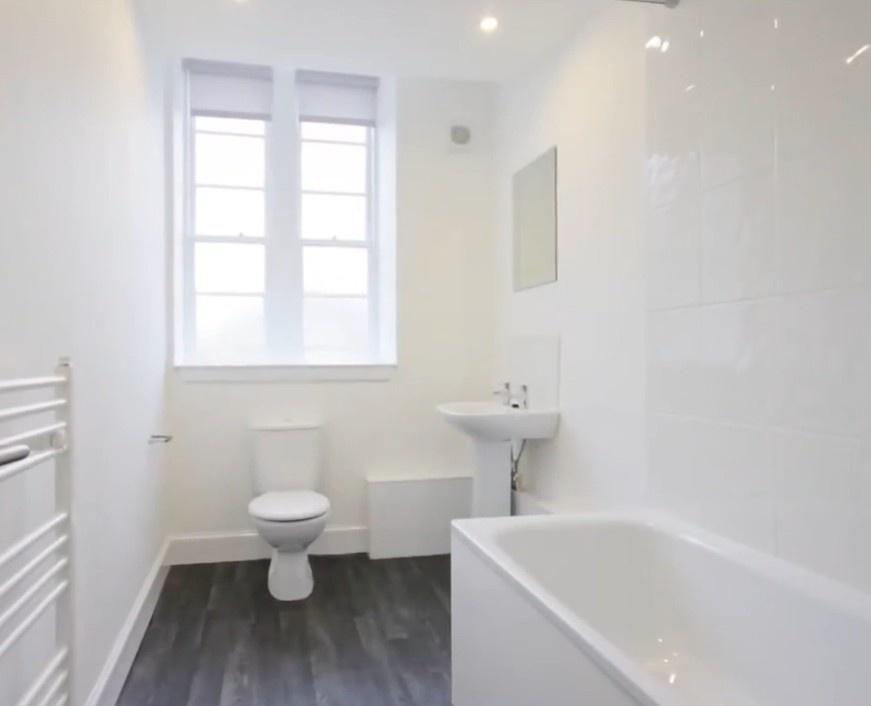 Bright white bathroom with bath and window...