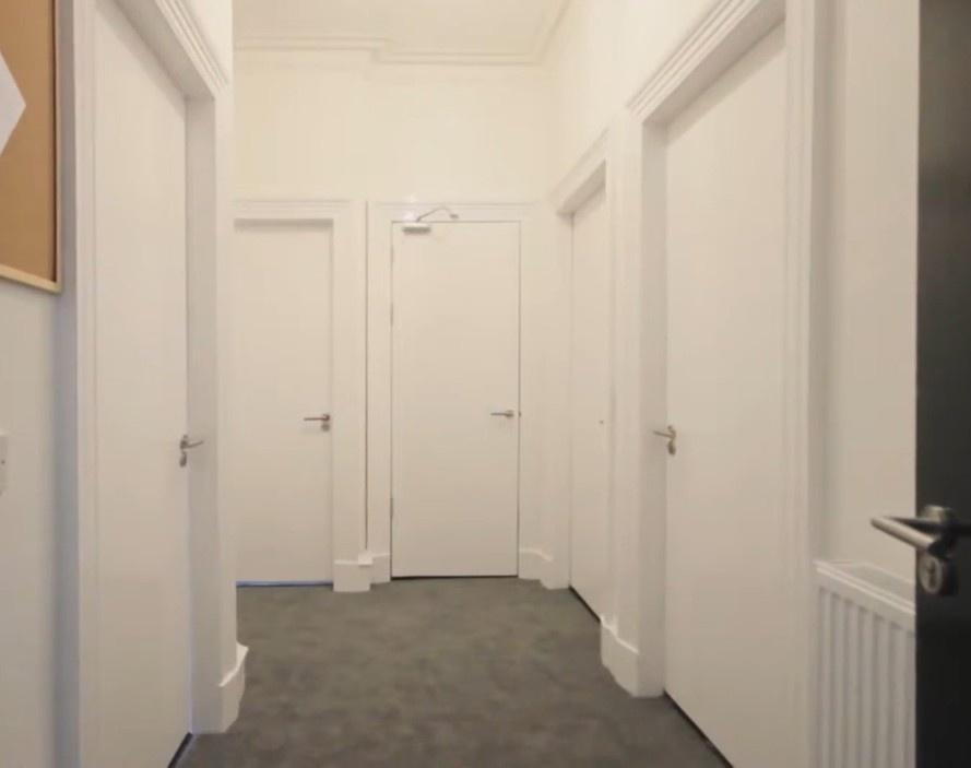 Bright neutral hallway with multiple doors...