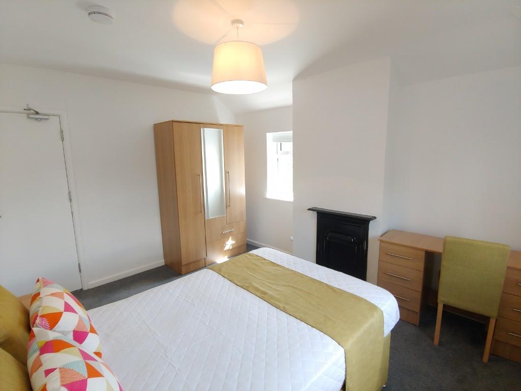 Bright furnished bedroom with bed and storage...