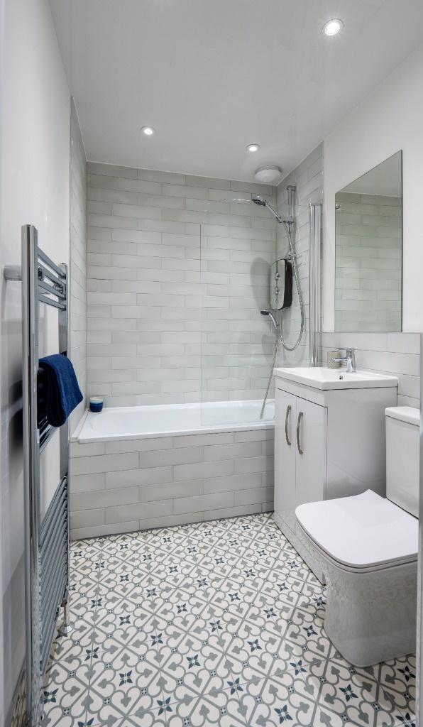 Modern tiled bathroom with bath and patterned t...