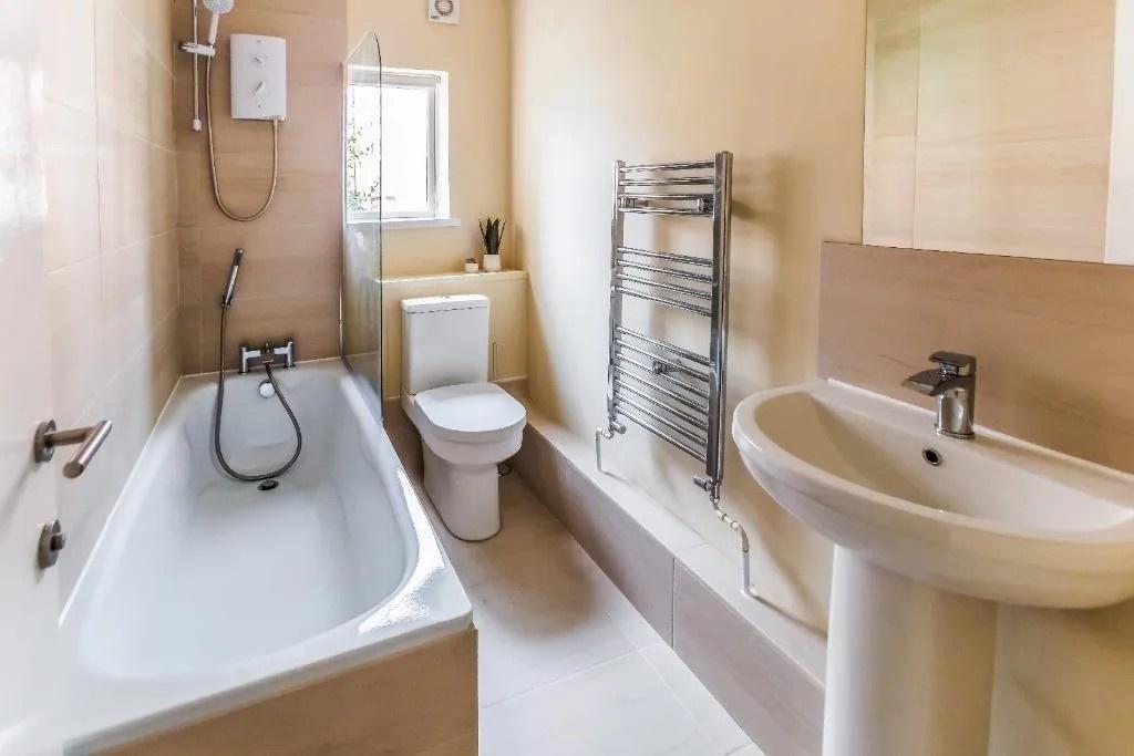 Bright bathroom with bath and heated towel rail...