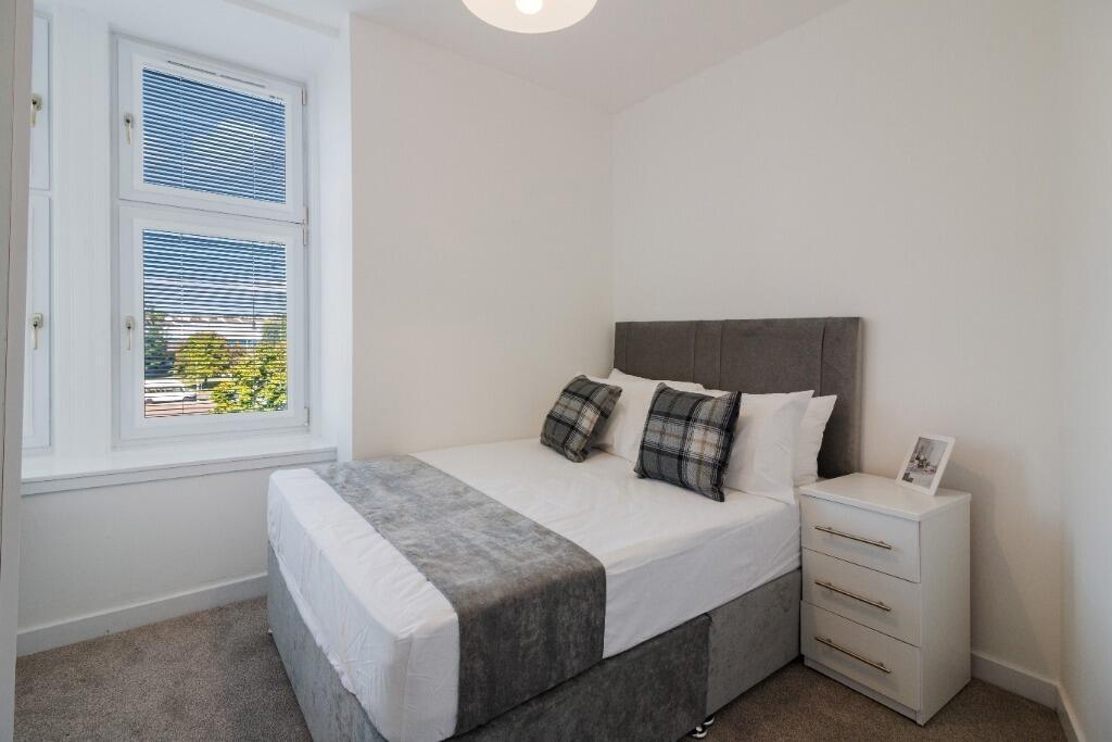 Bright double bedroom with stylish bed and wind...