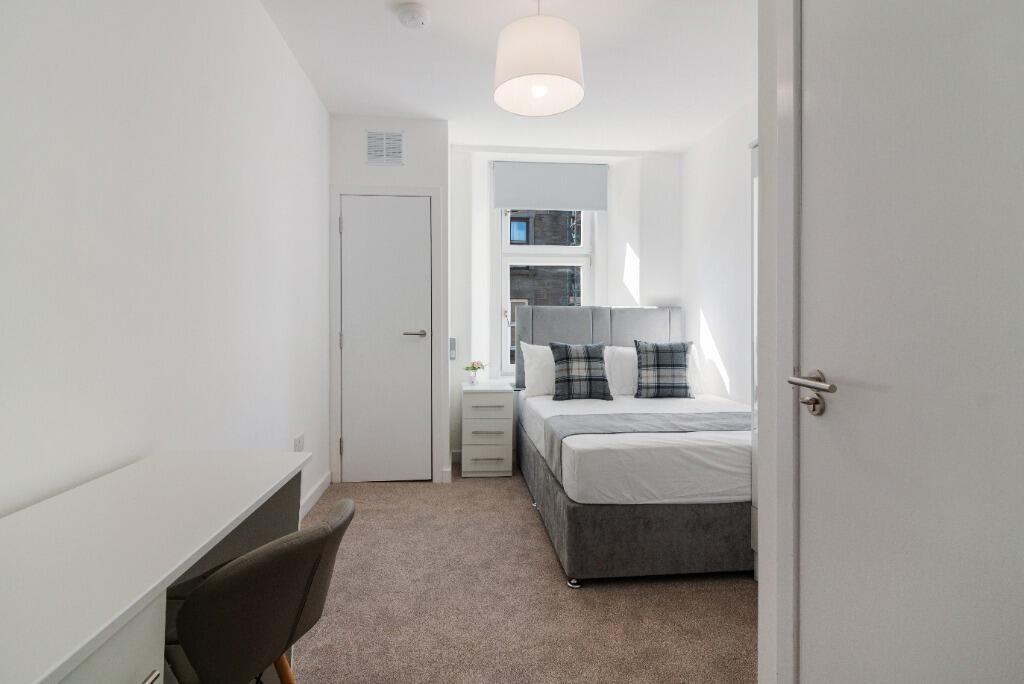 Bright, neat bedroom with desk and wardrobe...