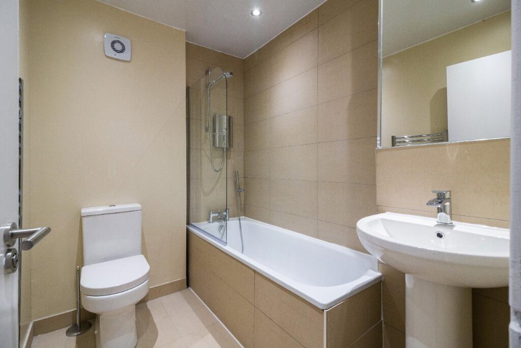 Modern bathroom with shower-over-bath and clean...