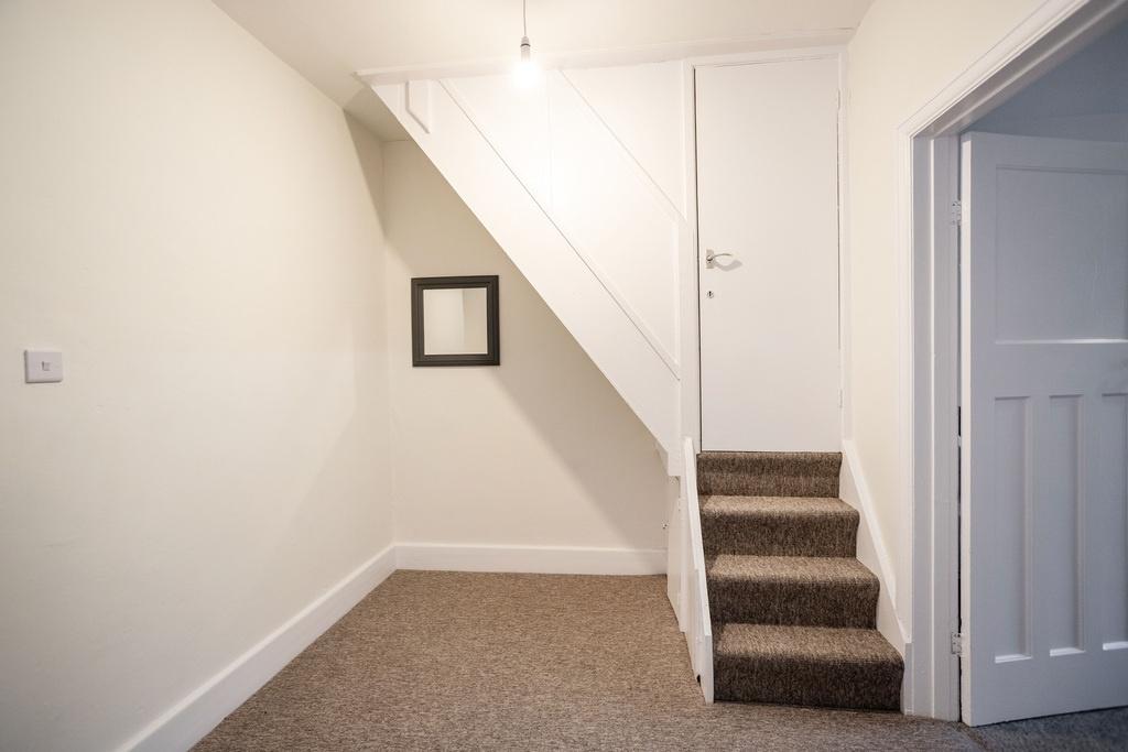 Neat entrance area with carpeted stairs, neutra...