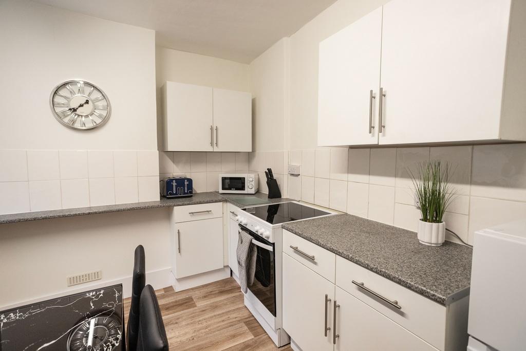 Bright modern kitchen with white cabinets, grey...