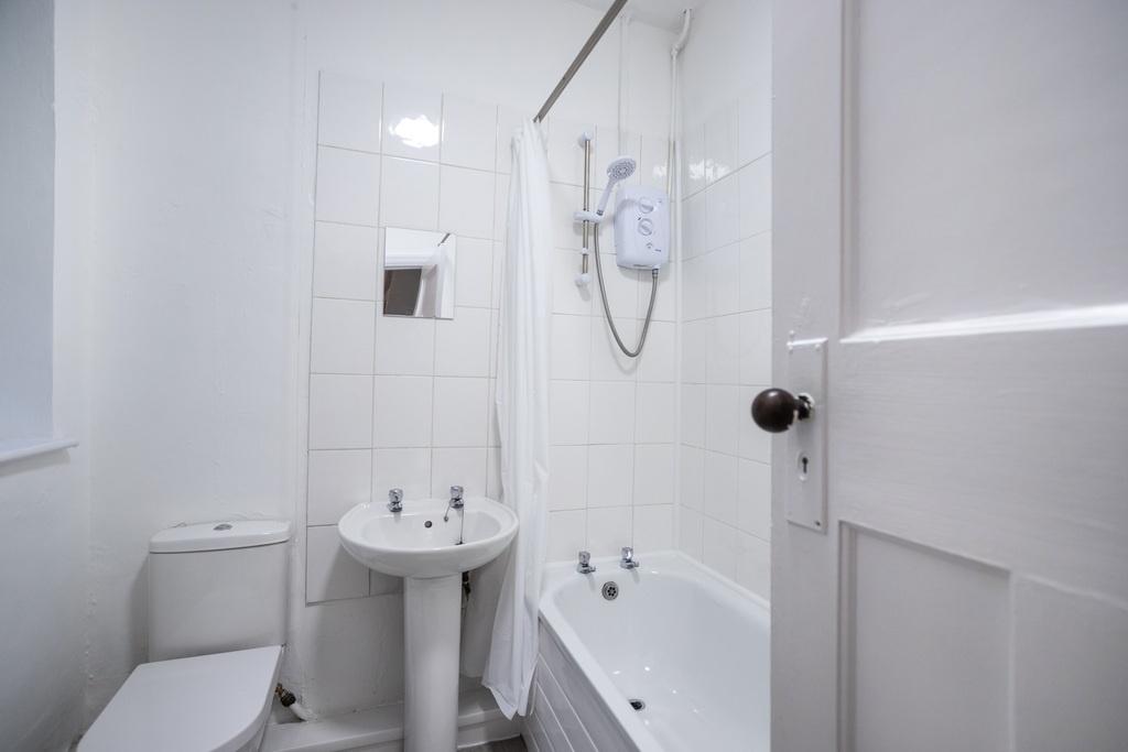 Bright, clean white bathroom with a bathtub and...