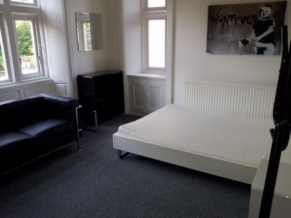 A bright and tidy bedroom featuring a comfortab...