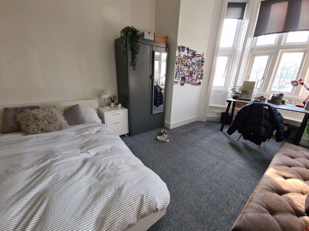 A spacious and bright bedroom featuring a comfo...