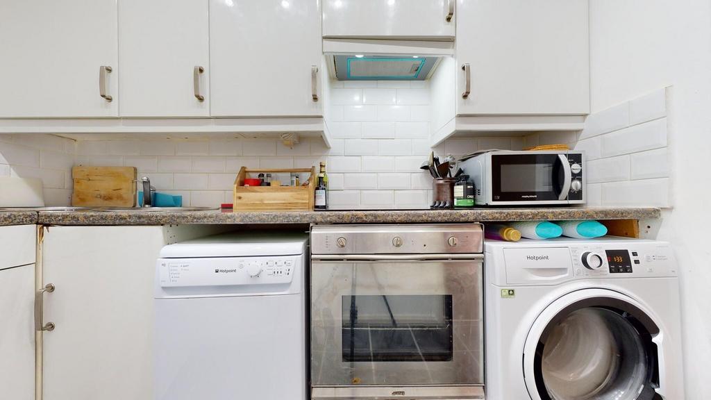 Bright fitted kitchen with white cabinetry, til...