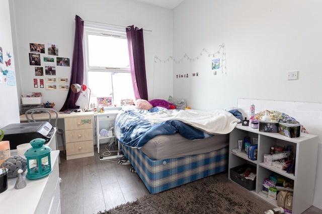 Bright, furnished bedroom with desk and storage...