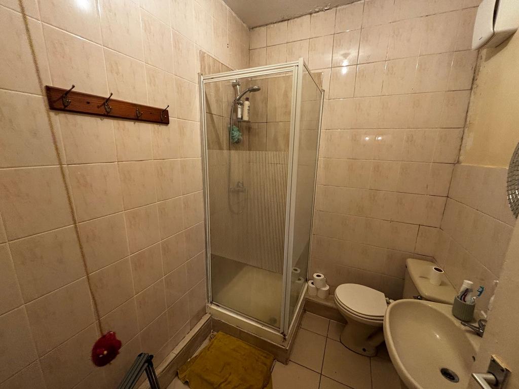 Compact tiled bathroom with a corner shower cub...