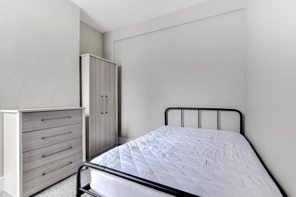Bright, simply furnished bedroom with a metal-f...