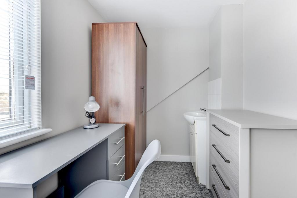 A bright, neatly maintained bedroom featuring a...