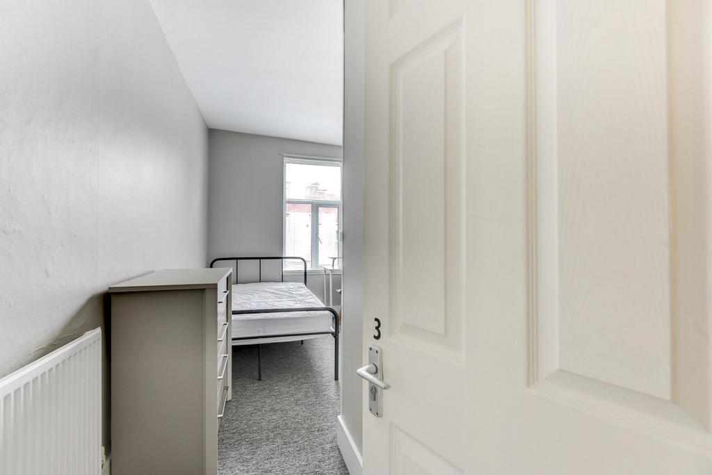 A bright, tidy student bedroom featuring a sing...