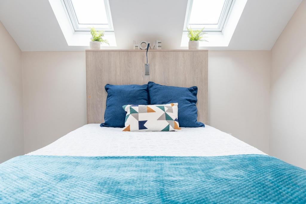 Bright, neatly made bedroom with a crisp white ...
