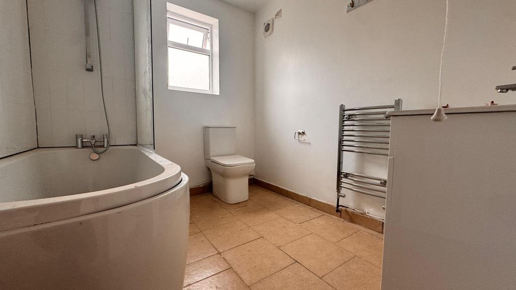 Bright bathroom with curved bath and towel rail...