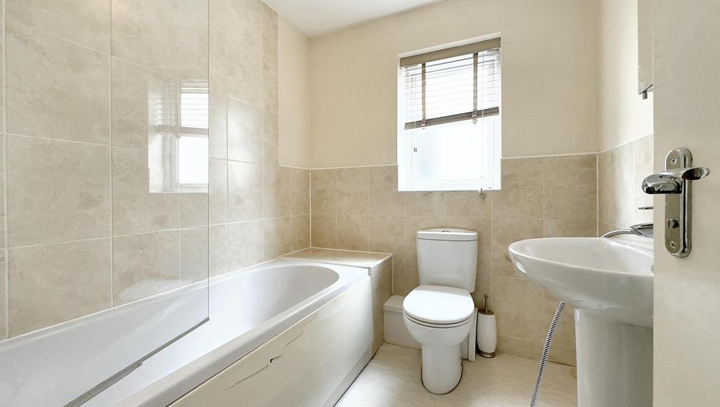 Bright modern bathroom with bath and tiled wall...