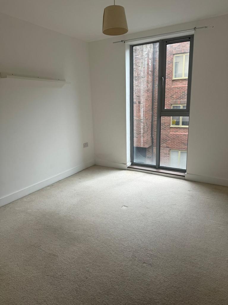 Bright room with tall window and neutral carpet...