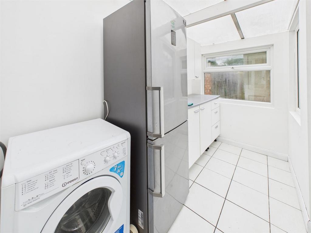 Bright galley kitchen with appliances and tiled...
