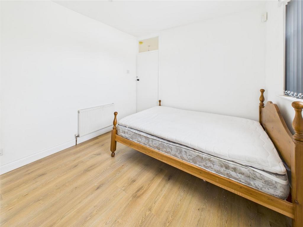 Bright, minimal bedroom with wooden bed and flo...