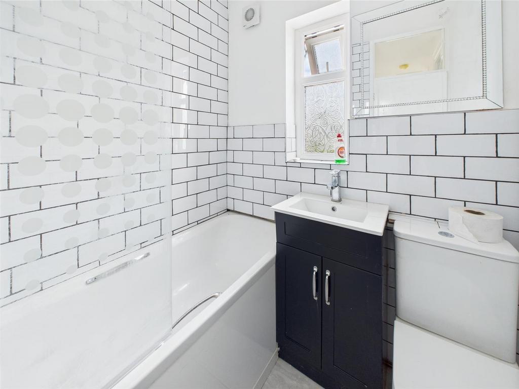 Bright, modern bathroom with tiled bath area...