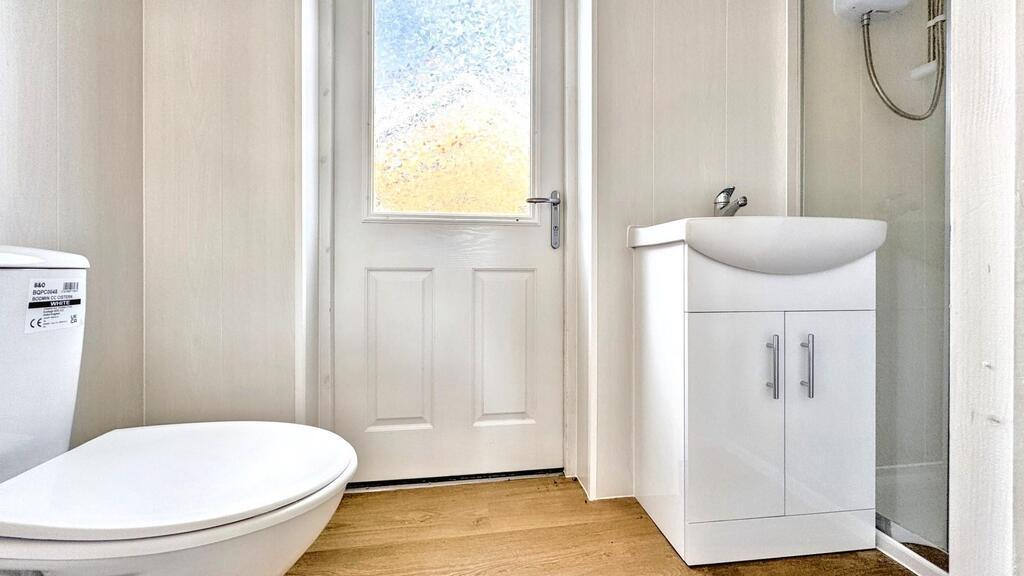 Bright bathroom with white suite and wood-effec...