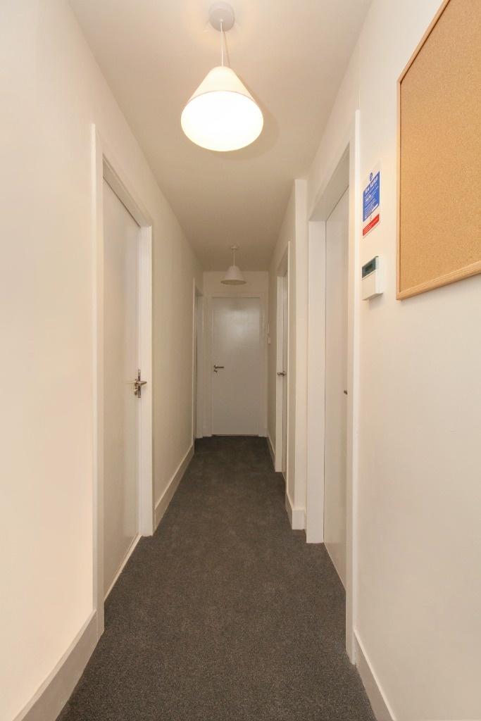 Bright, neutral communal hallway with notice bo...