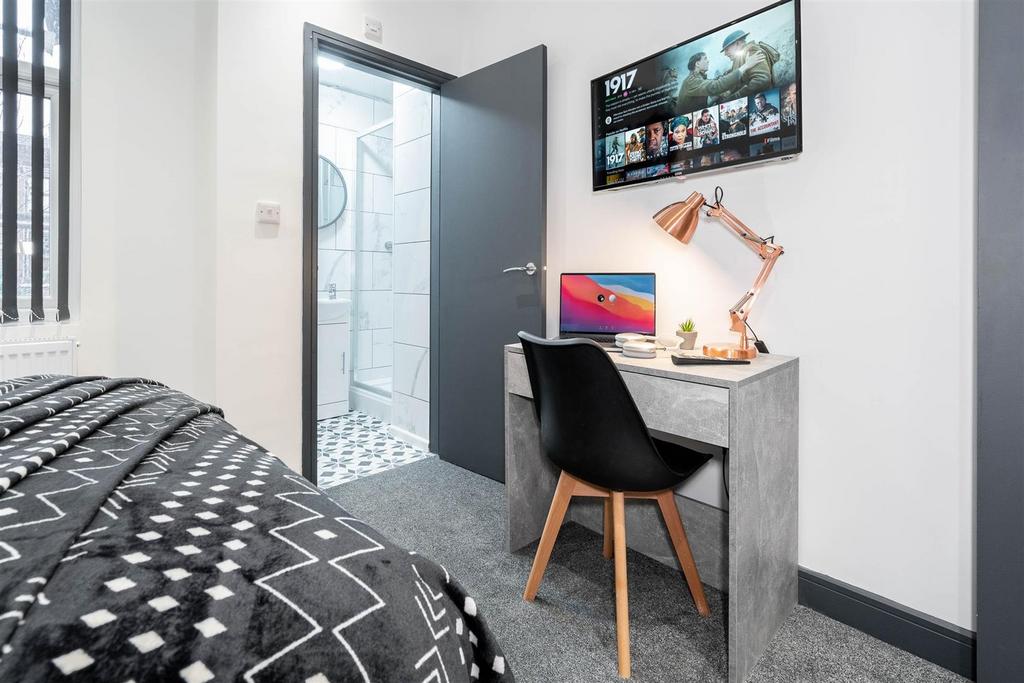 Bright, modern bedroom with desk and TV...