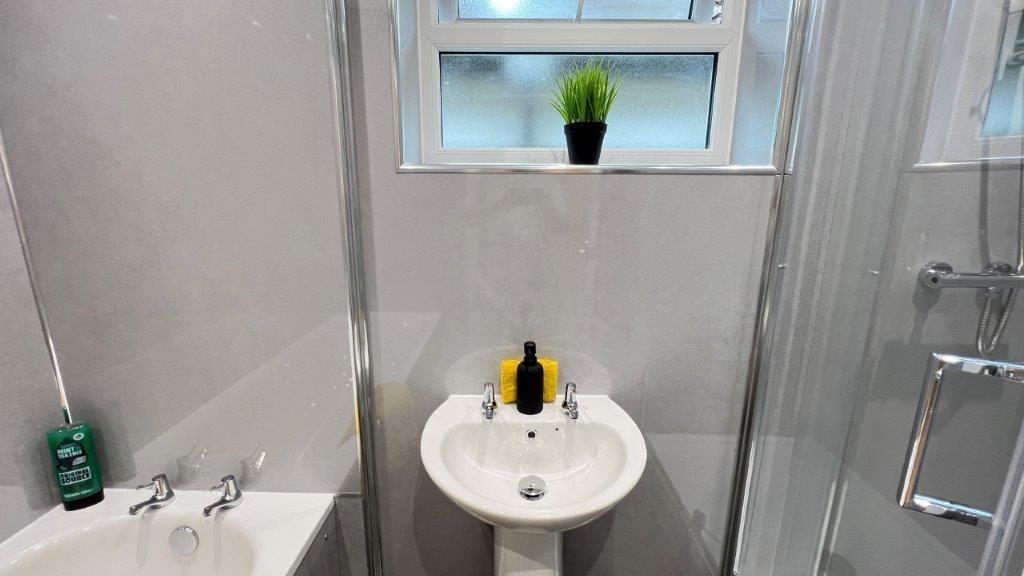 Bright clean bathroom with shower and basin...