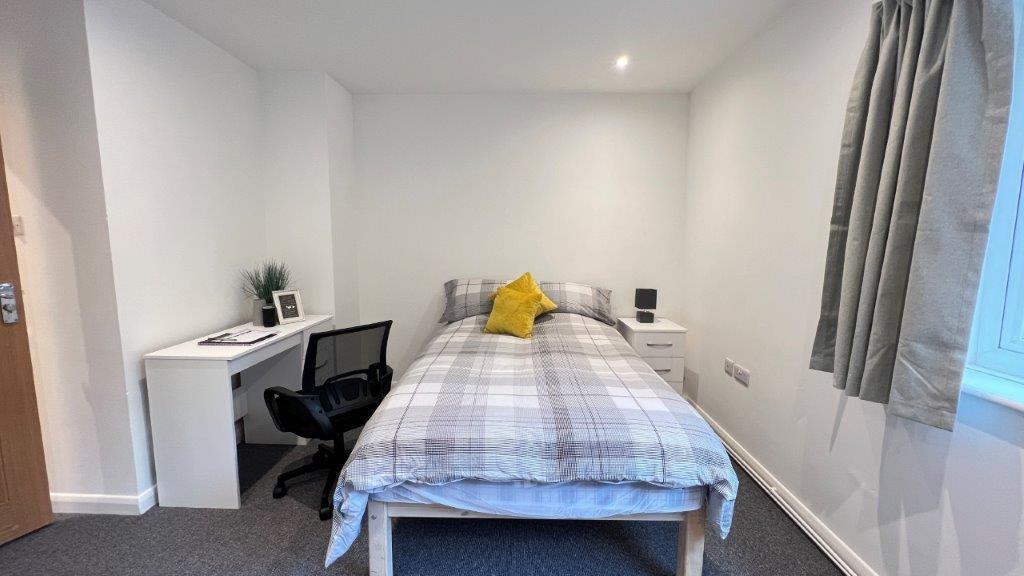 Bright, neat bedroom with desk and storage...