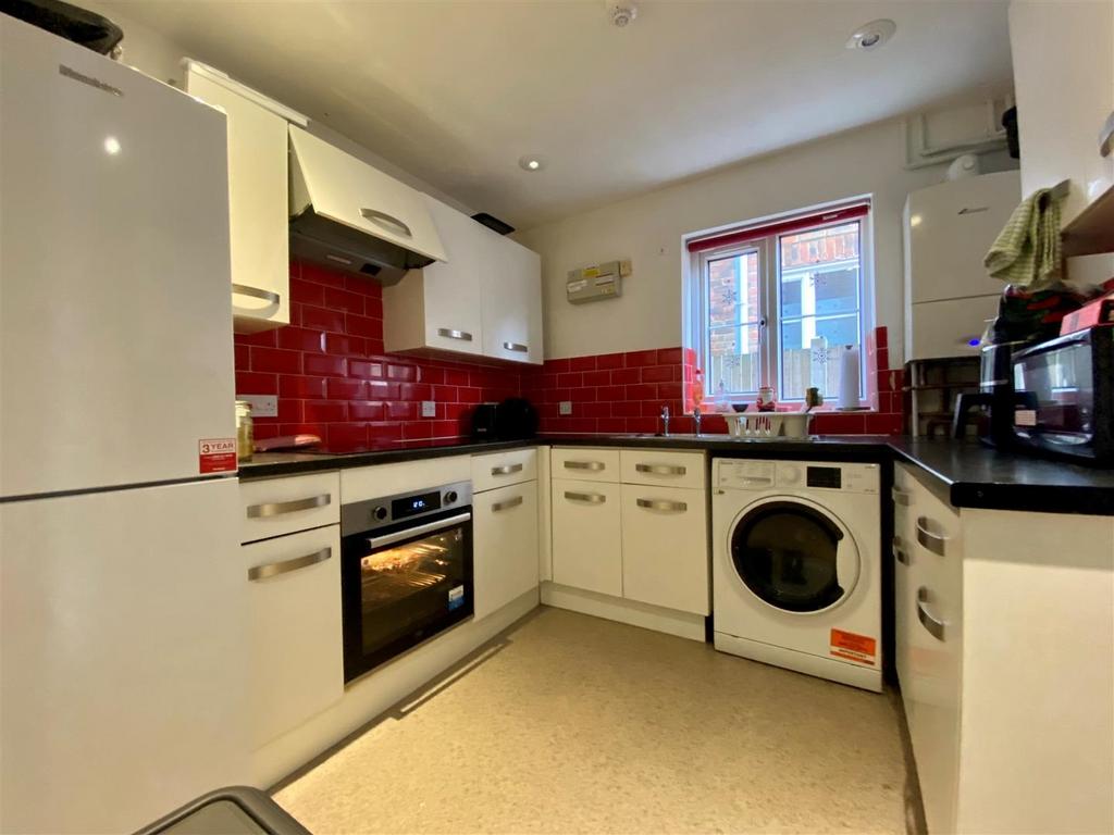 Modern kitchen with red tiled splashback and wh...