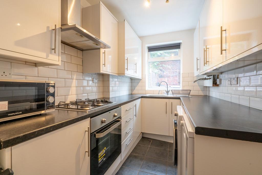 Modern kitchen with white cabinetry, black coun...