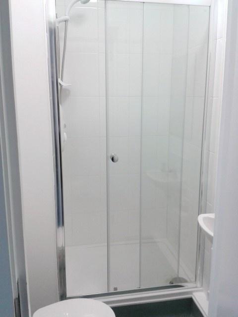 Bright, modern shower room with glass doors...