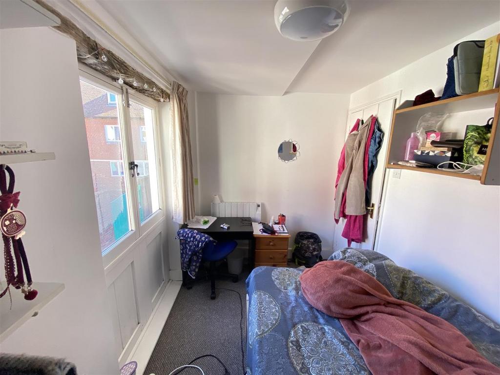 Bright single bedroom with bunk-style shelving...