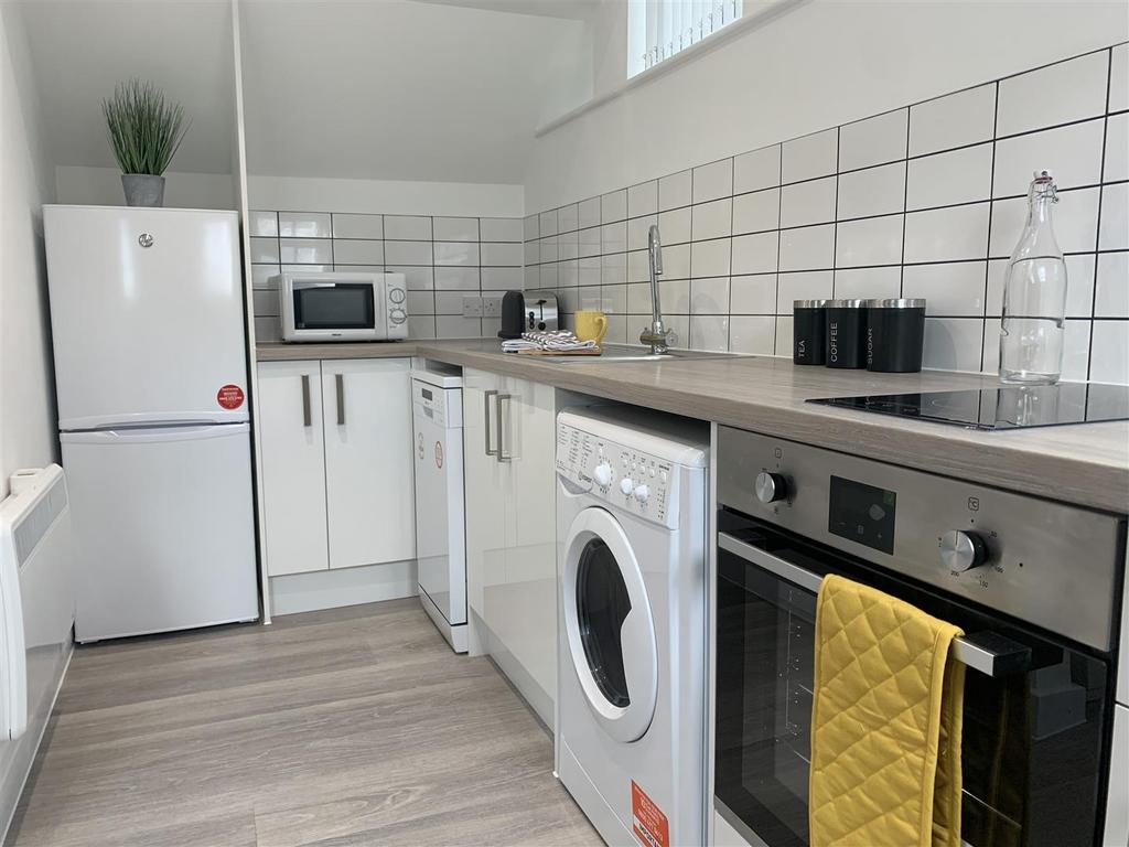 Modern fitted kitchen with appliances and tiled...