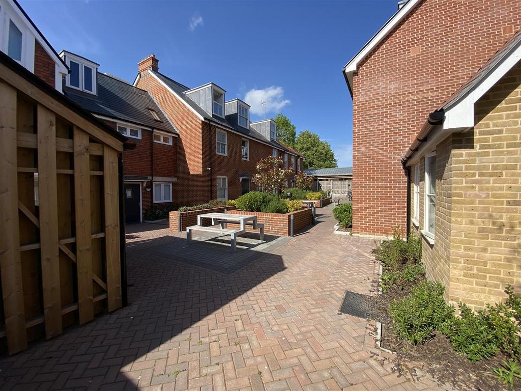 Sunny communal courtyard with seating and plant...
