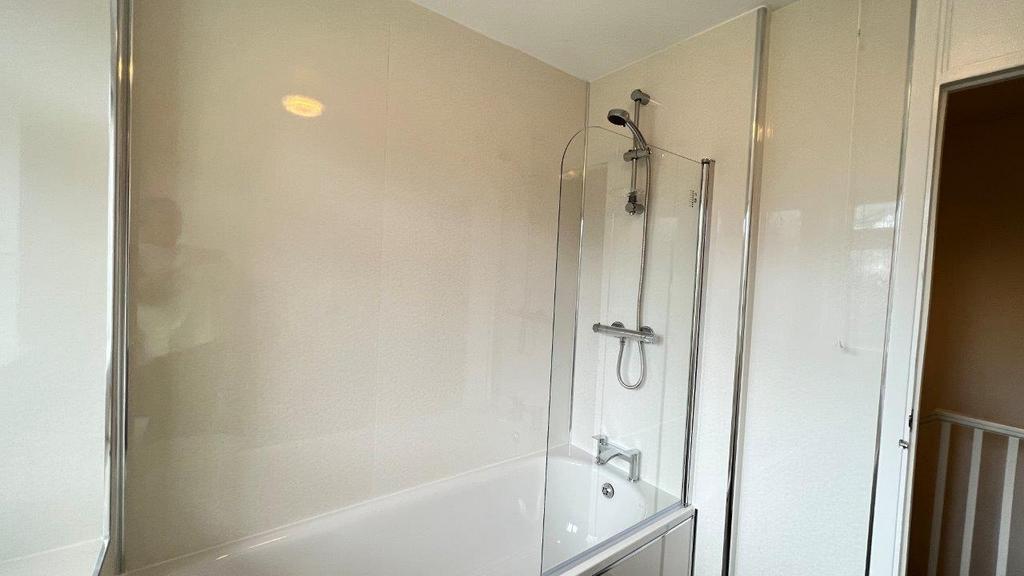 Clean modern bathroom with shower-over-bath...