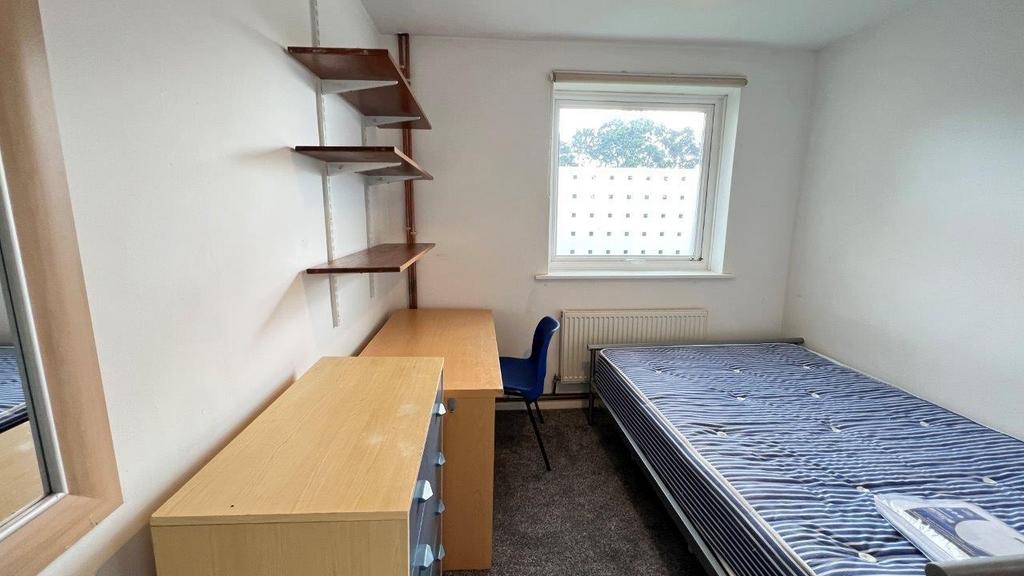 Simple furnished room with desk and bed near a ...