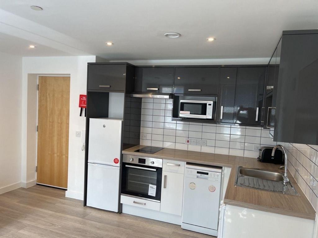 Modern fitted kitchen with appliances and tiled...