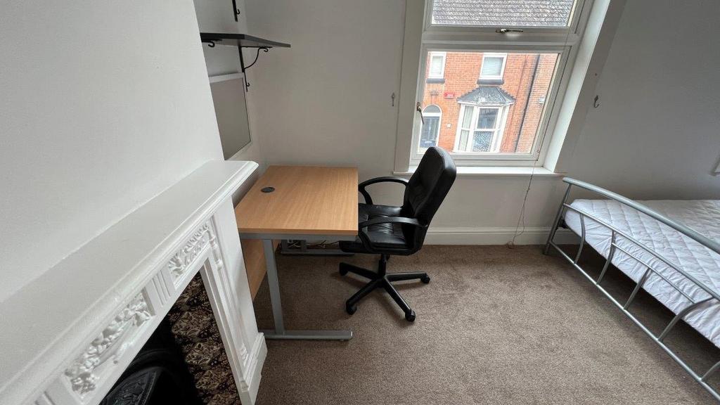 Bright bedroom with desk, bed and decorative fi...